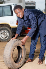 Fototapeta na wymiar Young woman mechanic with a tire in car workshop