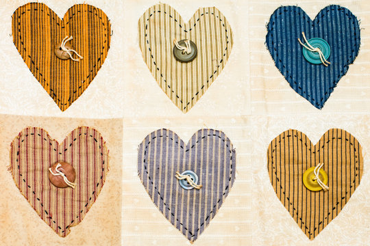 Old antique quilt with heart design and button centers. Warm tones with stripes in the squares of the quilt sampler.