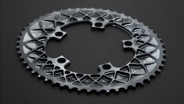 Grey bicycle oval chainring rotate at dark background in loop