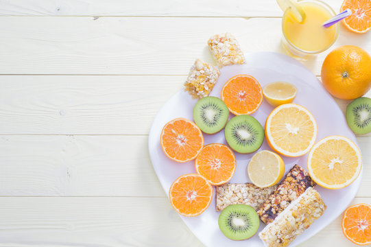 The concept of healthy breakfast, orange juice, fruit and cereal bars, flat lay on wooden table with copy space. Good morning, still life. Wonderful breakfast, energy boost for the day.