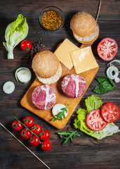 Ingredients for making homemade burger on wooden cutting board