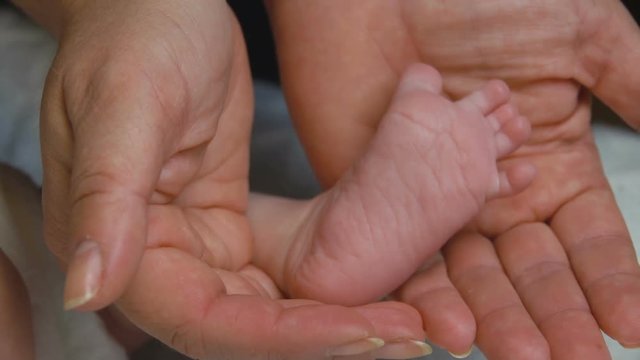 Baby's leg in the hand of an adult
