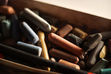 Pastel crayons piled in a box. Backlight.