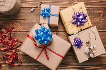 From above view of small wrapped presents decorated with colorful ribbons on wooden desk.