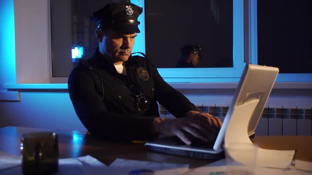 police officer USA working on laptop in the office over the disclosure of the crime, the investigation