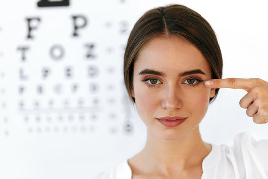 Closeup Of Smiling Young Woman In Front Of Visual Eye Test Board
