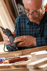 Senior carpenter carving wood with engraver tool. Restoring the old furniture.