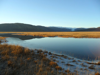 Reflection of mountain range and blue sky on a freezing lake, the southern part of Iceland 