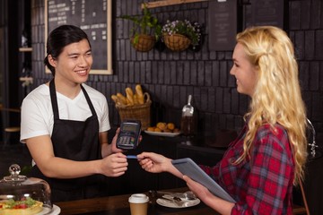 Smiling barista taking credit card from customer