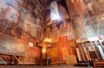 Fresco wall and candle lights inside the hall of Church of the Archangels, Georgia. - obrazy, fototapety, plakaty