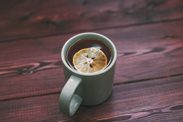 cup of tea with a slice of lemon on a wooden table. Background