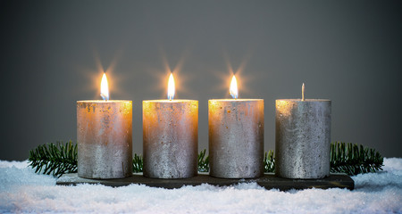 Dritte Advent - Vier silberne Adventskerzen mit drei angezündeten Kerzen