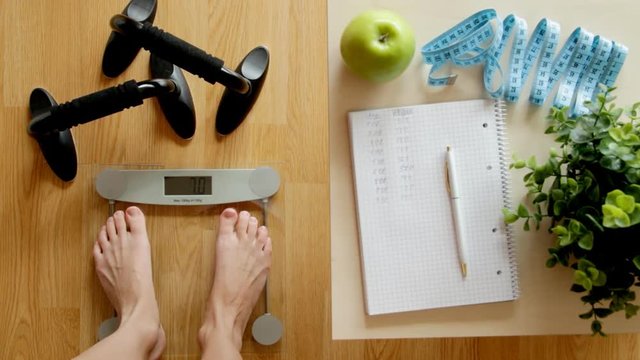 Fitness and weight loss concept, green apple, scale, tape measure and notebook on a wooden table, top view