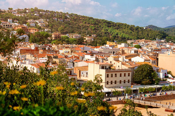 Aerial view of European town on a natural hills with many bars, hotels and restaurants in sunny day with blue sky. Tossa De Mar, Costa Brava, Spain.