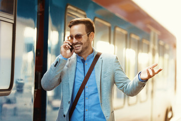 Business person is waiting for train and speaking on phone.