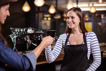 Pretty barista giving coffee to female customer