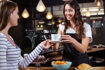 Smiling barista giving white cup to woman