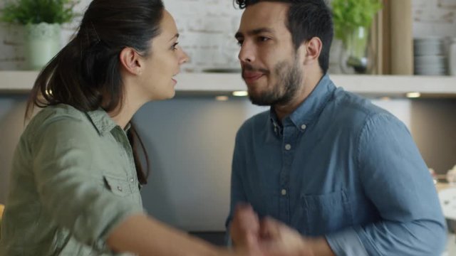 Young Couple Quarrels in the Kitchen. Man and Woman Scream  in Frustration and Angrily Gesticulate. Slow Motion. Shot on RED Cinema Camera in 4K (UHD).