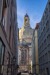 Fototapeta na wymiar View down a narrow street, famous Frauenkirche in the background, iluminated by warm sunlight.
