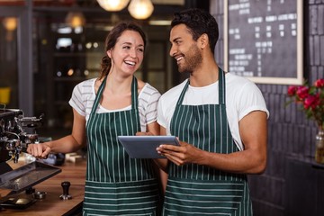 Smiling baristas using tablet