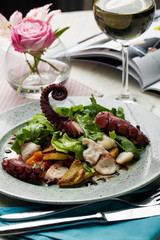 Octopus salad with arugula salad mix and a full wine in a restaurant
