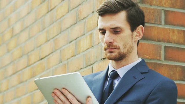 Young Businessman Being Outdoors and Using a Tablet Computer
