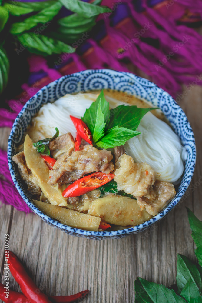 Wall mural Thai Green Curry with Pork on Thai Fabric and  Old Wooden Backgr