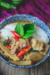 Thai Green Curry with Pork on Thai Fabric and  Old Wooden Backgr