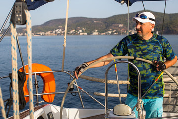 A man stands at the helm and operates the sailing vessel.