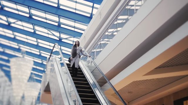 Full length of confident elegant businesswoman standing on escalator. Girl in mall