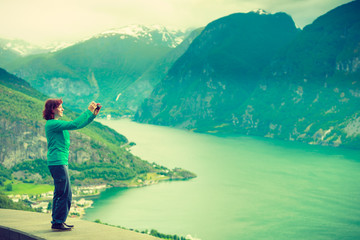 Fototapeta na wymiar Female tourist taking photo at norwegian fjord