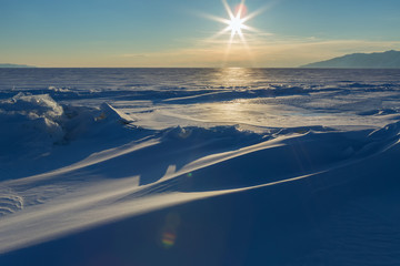 Obraz premium Sun sets over the snow-covered ice hummocks of Lake Baikal