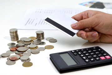 A business man hand using the calculator with coin stacks and financial report on the table 