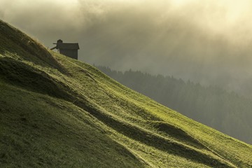 Dawn light rays on meadows of Sesto in Pustertal, South Tyrol, Italy