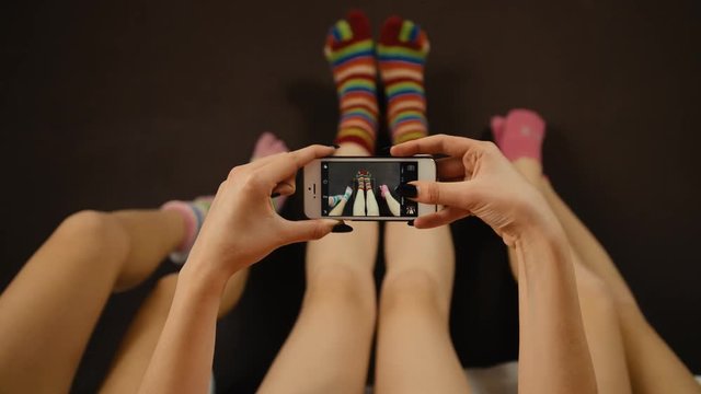 Close up of three friends taking pictures of colorful socks on a black smartphone.