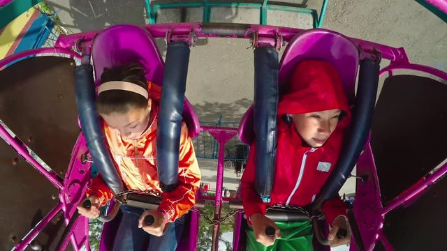 POV shot of boy and girl moving upside and down on swing in amusement park