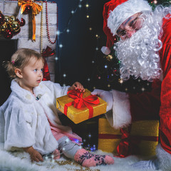Santa and girl playing near fireplace, decorated Christmas tree