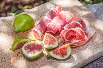 Ripe fig fruits and bacon or prosciutto. Food to accompany the d