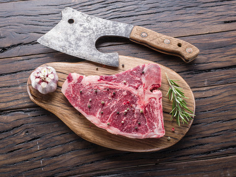Steak T-bone with spices on the wooden cutting board.