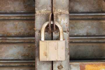 Dirty padlock on rusty steel shutter door