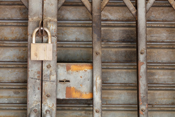 Dirty padlock on rusty steel shutter door