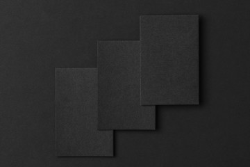 Mockup of three vertical business cards at black textured paper