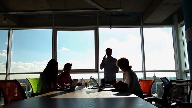 Business people having meeting in board room office. Men and women communicating while their boss speaking over mobile or smart phone abd receiving document from worker.
