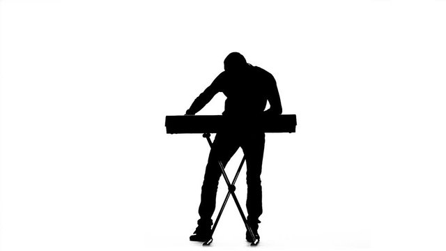 Young man having fun playing the piano. Silhouette. Slow motion