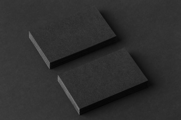 Mockup of two blank business cards stacks at black paper
