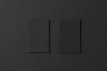 Mockup of two vertical business cards at black textured paper 