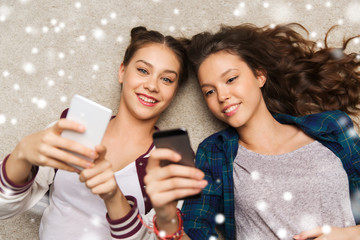 happy teenage girls lying on floor with smartphone