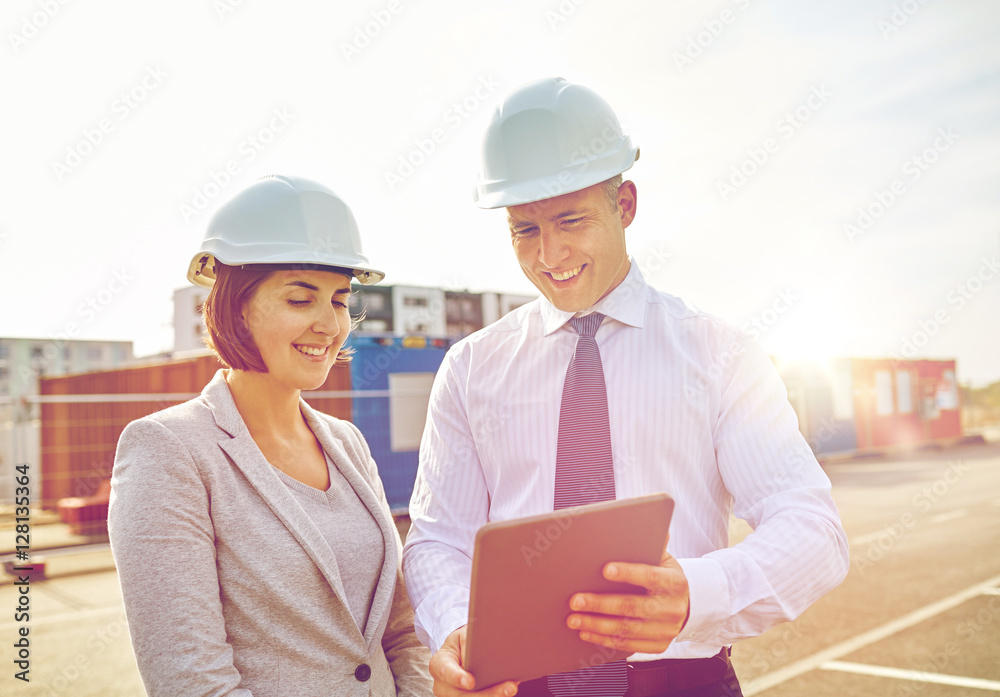 Sticker happy builders in hardhats with tablet pc outdoors