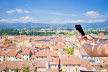 Closeup of male hands is holding cellphone background old italian town. Man using mobile smartphone.