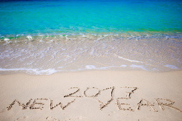 Fototapeta na wymiar 2017 New Year written in the white sand